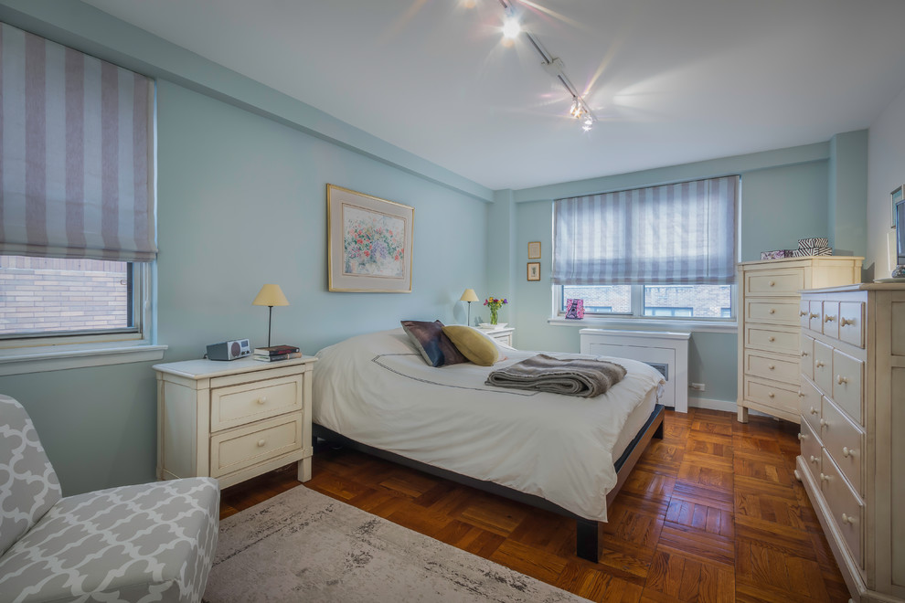 This is an example of a small traditional master bedroom in New York with blue walls, medium hardwood floors and brown floor.