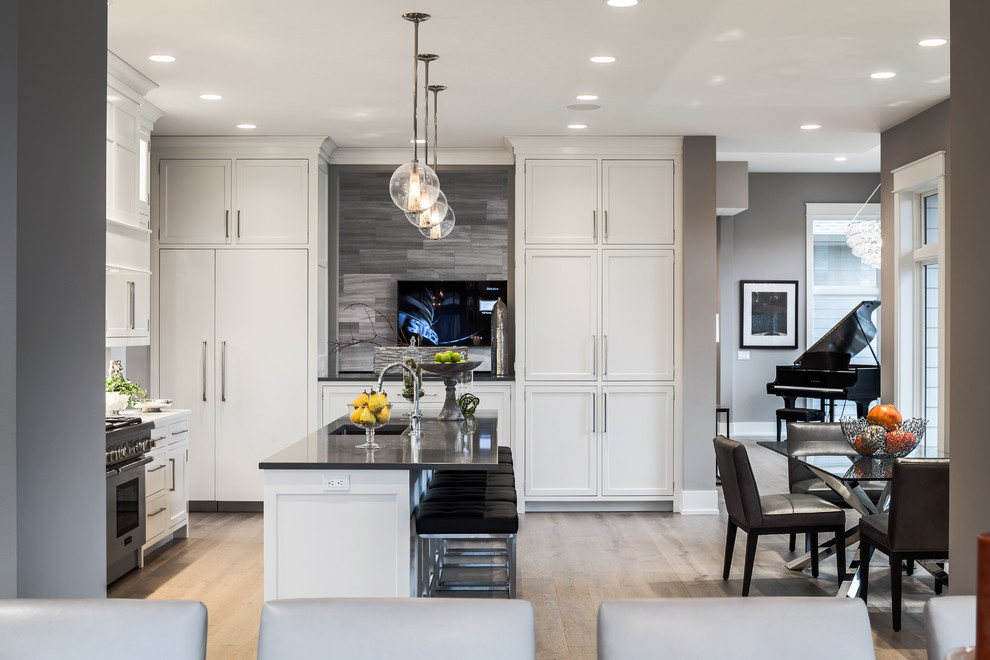 This is an example of a large transitional u-shaped eat-in kitchen in Grand Rapids with recessed-panel cabinets, grey cabinets, quartzite benchtops, beige splashback, matchstick tile splashback, stainless steel appliances, light hardwood floors and with island.