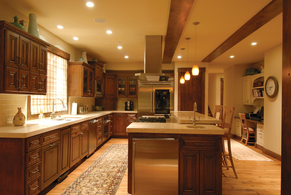 Inspiration for a mid-sized rustic l-shaped light wood floor and beige floor enclosed kitchen remodel with an undermount sink, raised-panel cabinets, dark wood cabinets, quartz countertops, white backsplash, subway tile backsplash, stainless steel appliances and an island