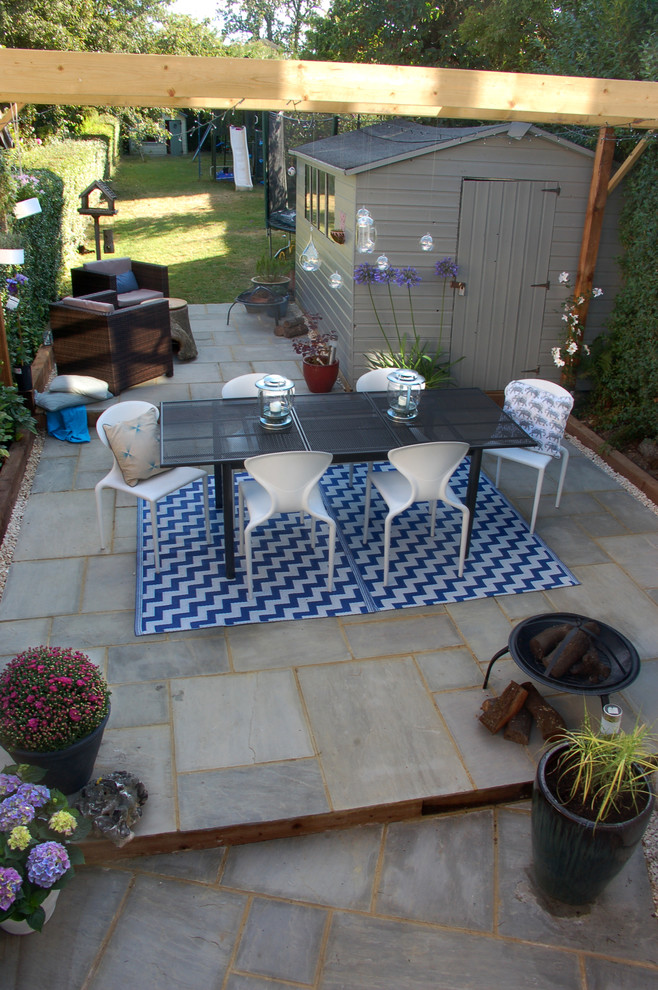 This is an example of a mid-sized contemporary backyard patio in Berkshire with a container garden, natural stone pavers and a pergola.