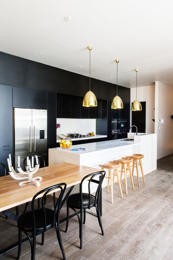 Contemporary galley eat-in kitchen in Melbourne with flat-panel cabinets, black cabinets, white splashback, light hardwood floors and a peninsula.