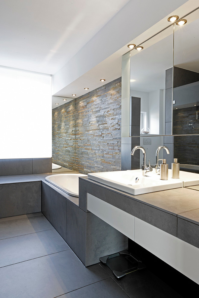 Mid-sized modern master bathroom in Cologne with flat-panel cabinets, white cabinets, a drop-in tub, brown tile, gray tile, stone tile, white walls, a drop-in sink, slate floors and engineered quartz benchtops.