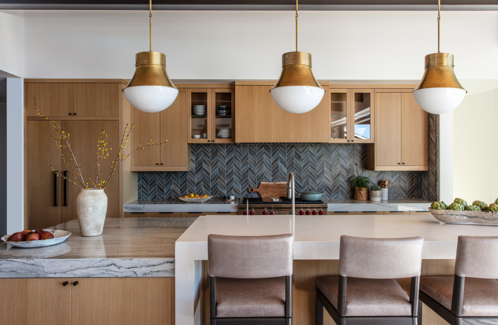 Zweizeilige Moderne Küche mit flächenbündigen Schrankfronten, hellbraunen Holzschränken, Küchenrückwand in Grau, Rückwand aus Mosaikfliesen, Küchengeräten aus Edelstahl, Kücheninsel und grauer Arbeitsplatte in Sonstige
