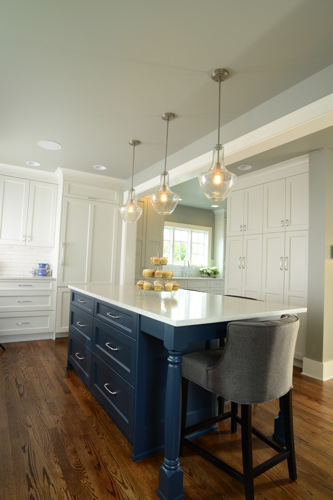 Inspiration for a large transitional single-wall medium tone wood floor eat-in kitchen remodel in Seattle with an undermount sink, shaker cabinets, white cabinets, quartz countertops, white backsplash, subway tile backsplash, paneled appliances and an island