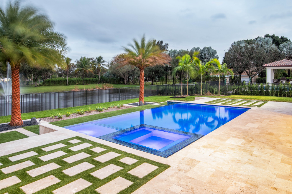 Large modern backyard rectangular infinity pool in Miami with with a pool and natural stone pavers.