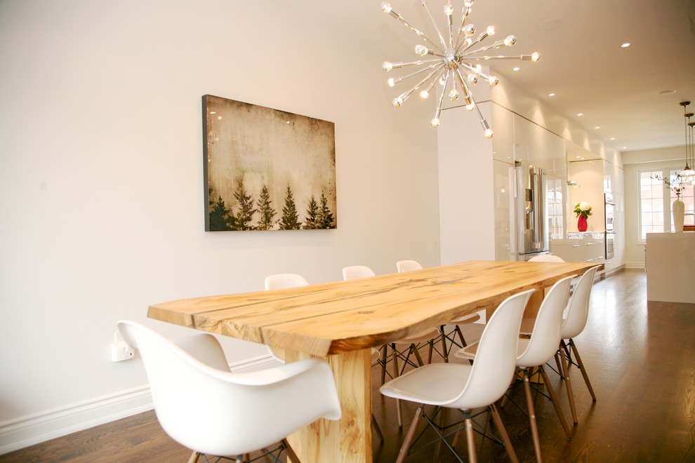 This is an example of a modern kitchen/dining combo in Toronto with white walls and dark hardwood floors.