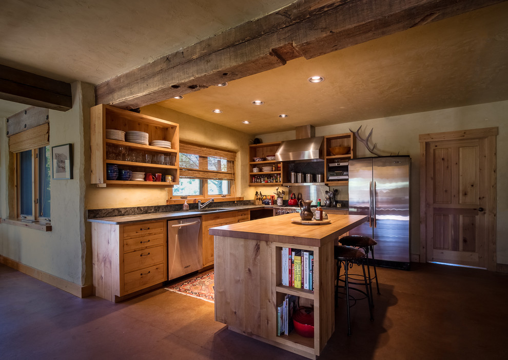 Design ideas for a mid-sized country l-shaped open plan kitchen in Other with an undermount sink, flat-panel cabinets, light wood cabinets, wood benchtops, stainless steel appliances, concrete floors, with island and brown floor.
