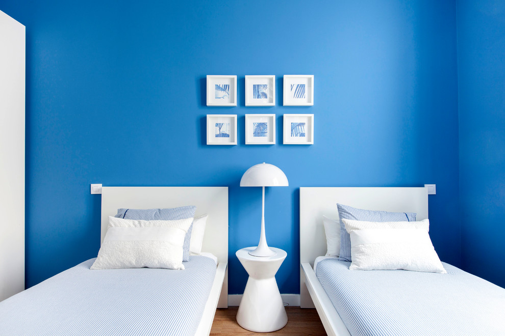 Photo of a mid-sized beach style guest bedroom in Madrid with blue walls, medium hardwood floors, no fireplace and brown floor.
