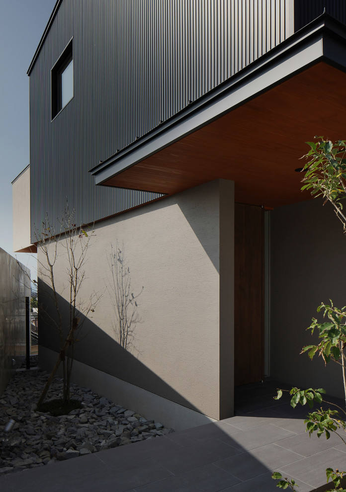 Large modern two-storey concrete black house exterior in Other with a shed roof, a metal roof, a black roof and board and batten siding.