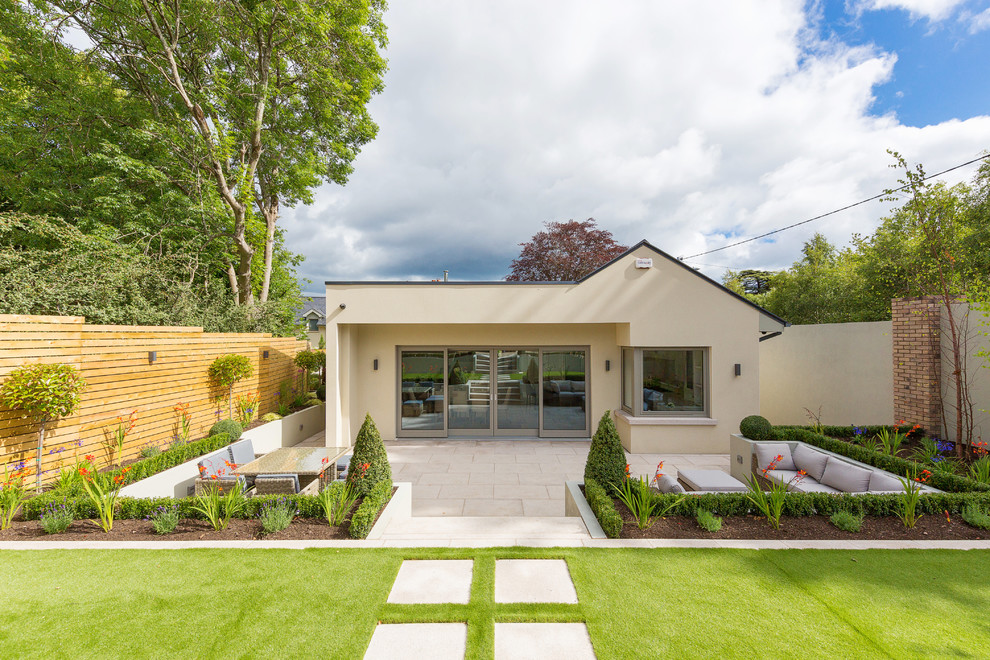 Photo of a mid-sized contemporary one-storey stucco beige house exterior in Dublin with a flat roof.