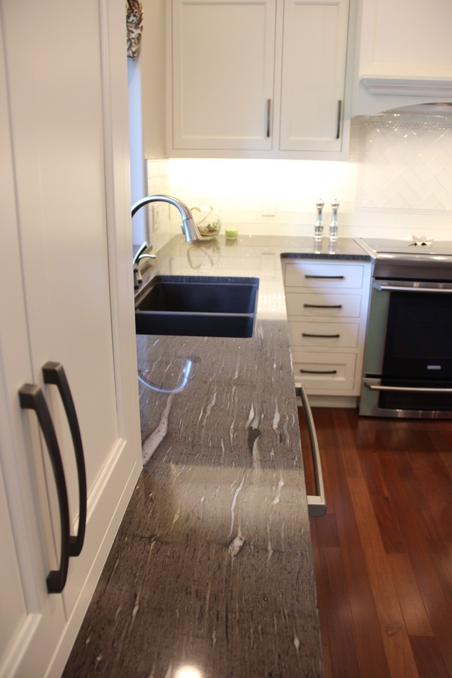 Inspiration for a mid-sized transitional l-shaped dark wood floor eat-in kitchen remodel with a double-bowl sink, shaker cabinets, white cabinets, granite countertops, white backsplash, glass tile backsplash, stainless steel appliances and an island
