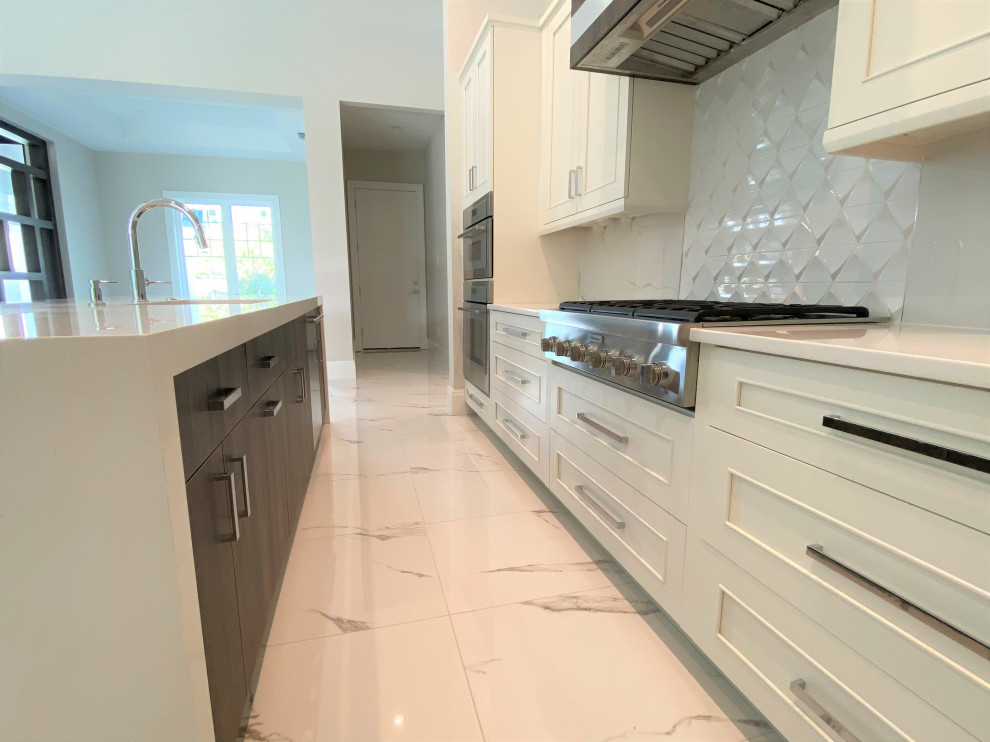 Example of a mid-sized transitional l-shaped porcelain tile and white floor open concept kitchen design in Miami with an undermount sink, recessed-panel cabinets, beige cabinets, quartz countertops, white backsplash, porcelain backsplash, stainless steel appliances, an island and white countertops