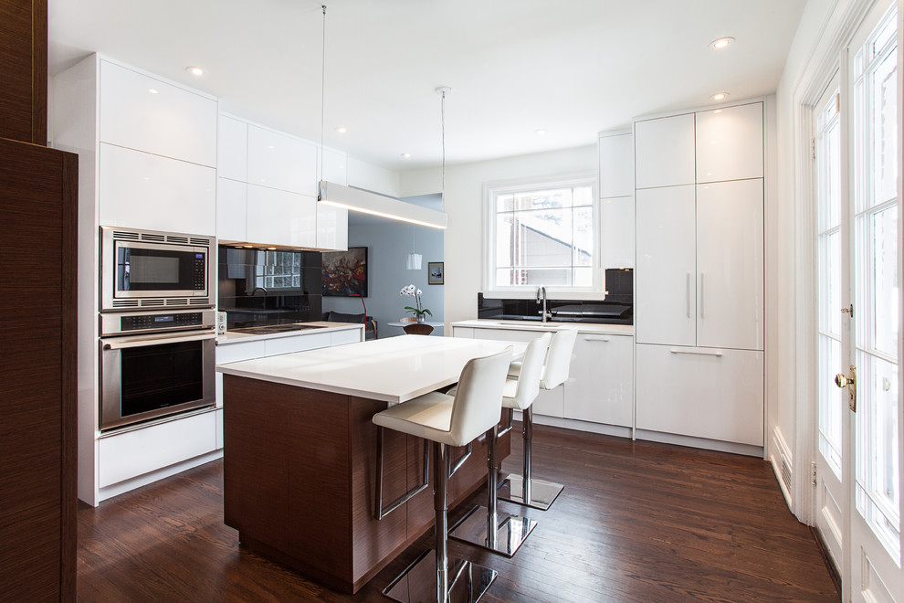 Large contemporary u-shaped eat-in kitchen in Ottawa with flat-panel cabinets, dark wood cabinets, black splashback, stainless steel appliances, a double-bowl sink, dark hardwood floors and with island.