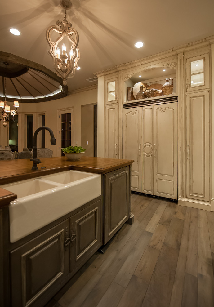 Photo of an expansive country u-shaped eat-in kitchen in Other with a double-bowl sink, raised-panel cabinets, distressed cabinets, wood benchtops, white appliances, light hardwood floors and with island.