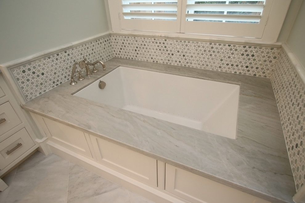Photo of a large traditional master bathroom in Houston with beaded inset cabinets, marble floors, a drop-in sink, limestone benchtops and an undermount tub.
