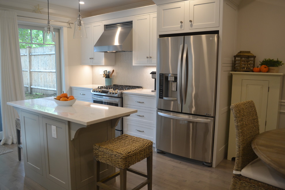 Photo of a small beach style u-shaped eat-in kitchen in Boston with a single-bowl sink, shaker cabinets, white cabinets, granite benchtops, multi-coloured splashback, marble splashback, stainless steel appliances, light hardwood floors, with island, grey floor and white benchtop.