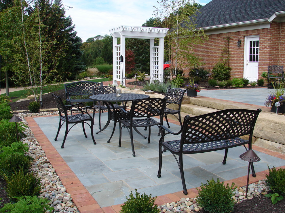 Inspiration for a large traditional backyard patio in Cleveland with natural stone pavers and no cover.
