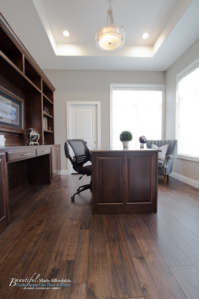 Inspiration for a mid-sized traditional home office in Other with beige walls, medium hardwood floors, a built-in desk and brown floor.