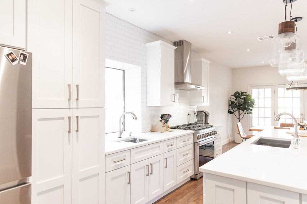 Inspiration for a mid-sized transitional medium tone wood floor and brown floor eat-in kitchen remodel in Phoenix with shaker cabinets, white cabinets, white backsplash, subway tile backsplash, stainless steel appliances and an island