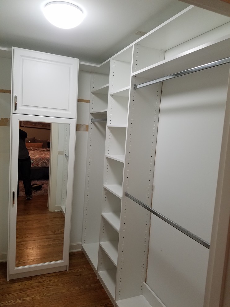 Photo of a small contemporary gender-neutral walk-in wardrobe in Louisville with open cabinets, white cabinets, medium hardwood floors and brown floor.