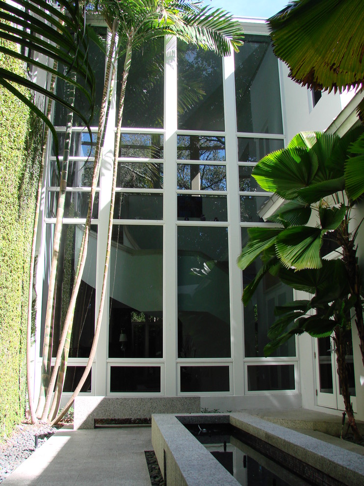 Photo of a large contemporary two-storey stucco white exterior in Miami with a hip roof.