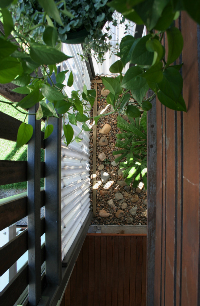 Inspiration pour un xéropaysage latéral minimaliste de taille moyenne et l'été avec une exposition partiellement ombragée, des galets de rivière et une clôture en bois.