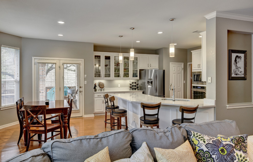 Eat-in kitchen - mid-sized transitional u-shaped light wood floor eat-in kitchen idea in Austin with an undermount sink, white cabinets, quartz countertops, white backsplash, stone slab backsplash, stainless steel appliances, a peninsula and raised-panel cabinets