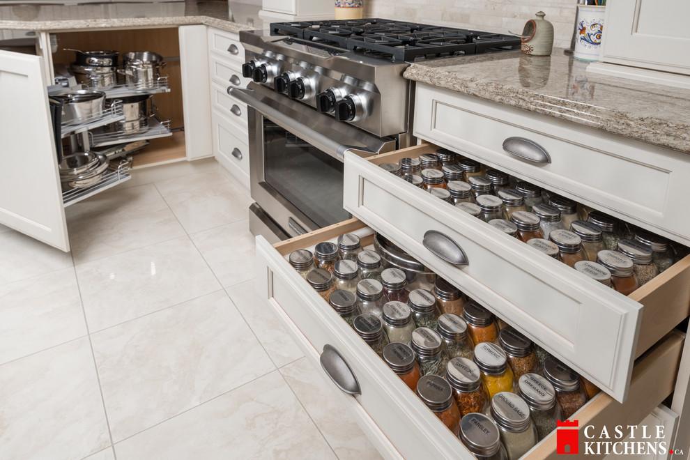 Enclosed kitchen - mid-sized transitional galley porcelain tile enclosed kitchen idea in Toronto with an undermount sink, shaker cabinets, beige cabinets, quartzite countertops, beige backsplash, stainless steel appliances and an island