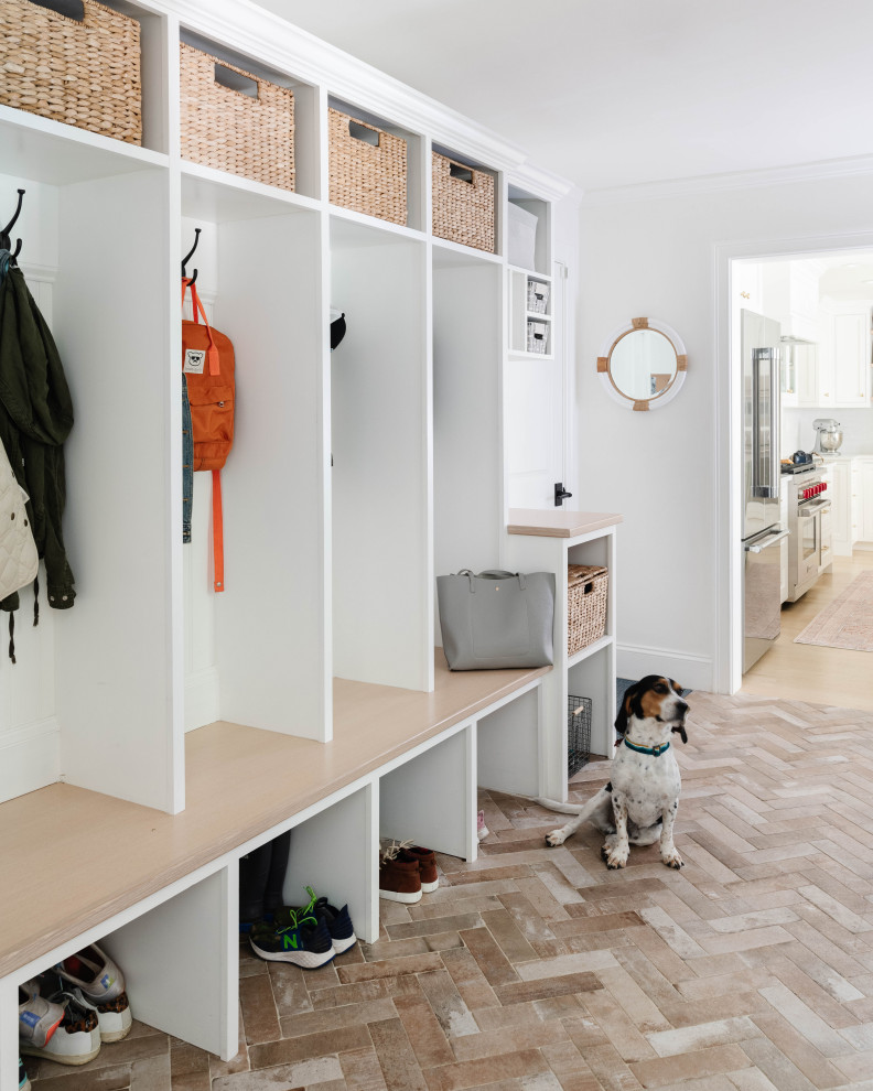 Large transitional mudroom in Boston with white walls and brick floors.
