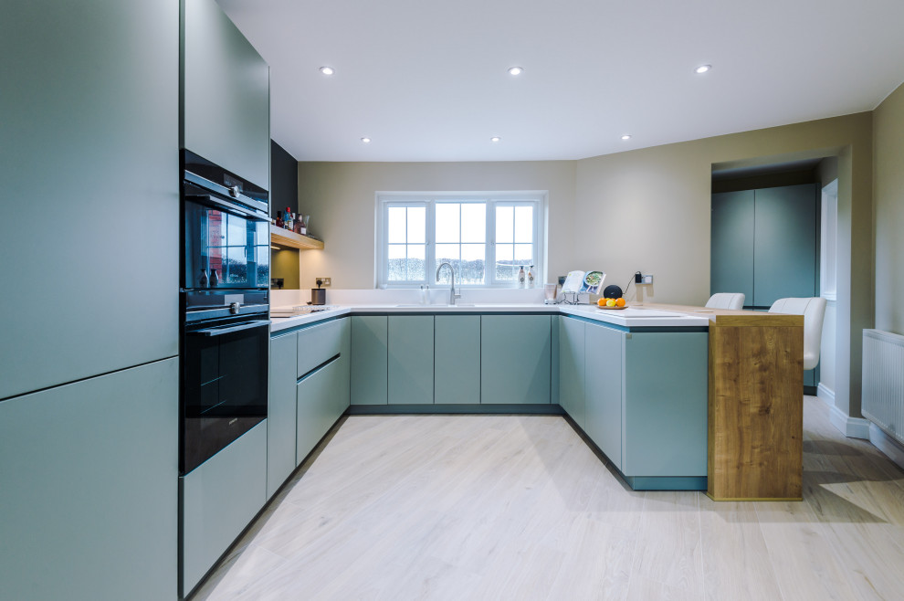 Design ideas for a mid-sized contemporary u-shaped kitchen in Manchester with a drop-in sink, blue cabinets and porcelain floors.