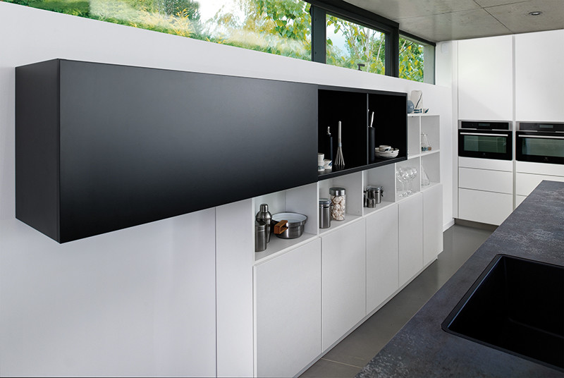 Contemporary galley kitchen in Moscow with an undermount sink, flat-panel cabinets, white cabinets, laminate benchtops, black appliances, porcelain floors and with island.