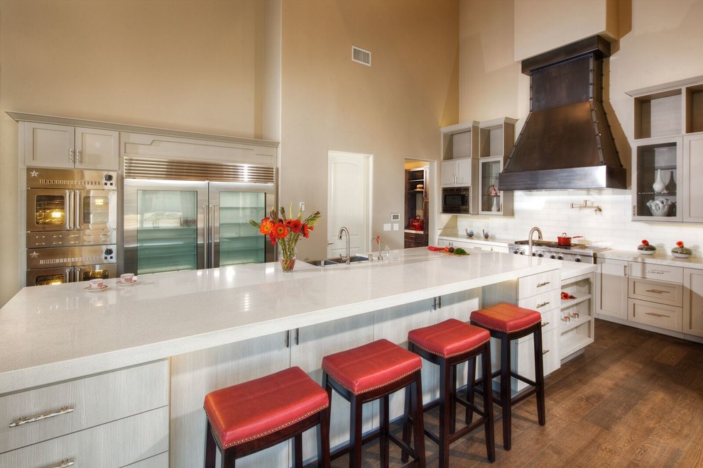 Eat-in kitchen - large transitional u-shaped medium tone wood floor eat-in kitchen idea in Sacramento with a farmhouse sink, solid surface countertops, white backsplash, subway tile backsplash, stainless steel appliances, an island, shaker cabinets and beige cabinets