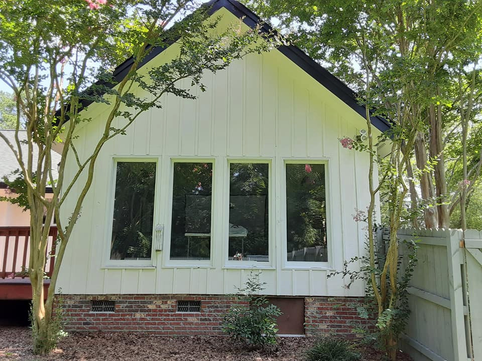 Foto della villa verde country a un piano di medie dimensioni con rivestimento in legno, tetto a capanna, copertura a scandole, tetto nero e pannelli e listelle di legno