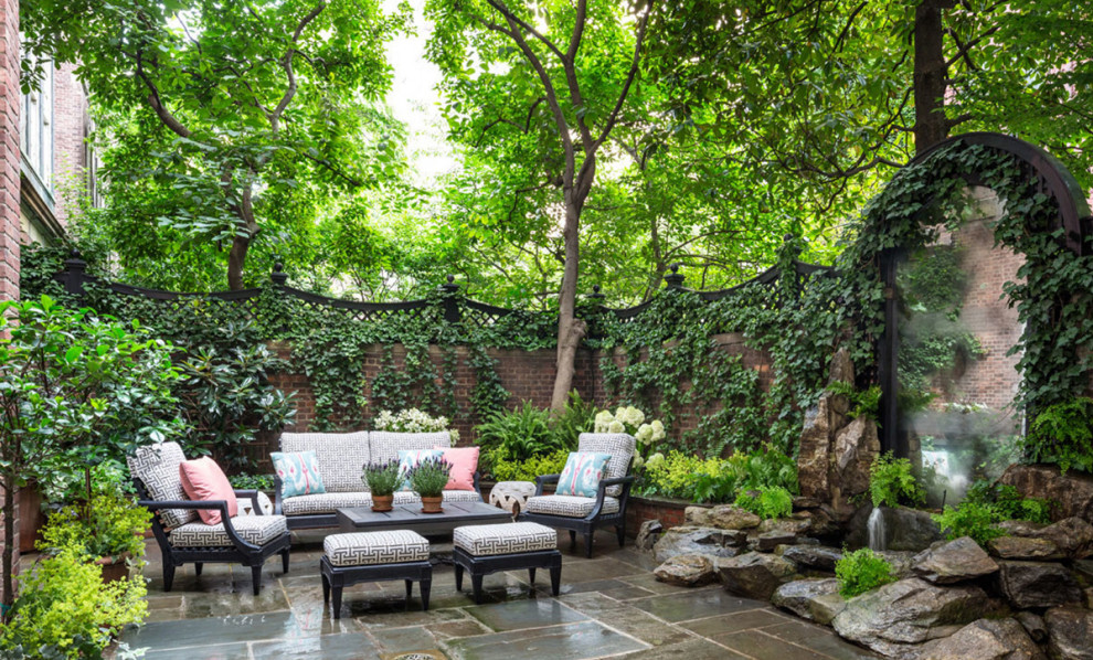 Photo of a large classic back formal partial sun garden in New York with a raised bed, natural stone paving and a stone fence.