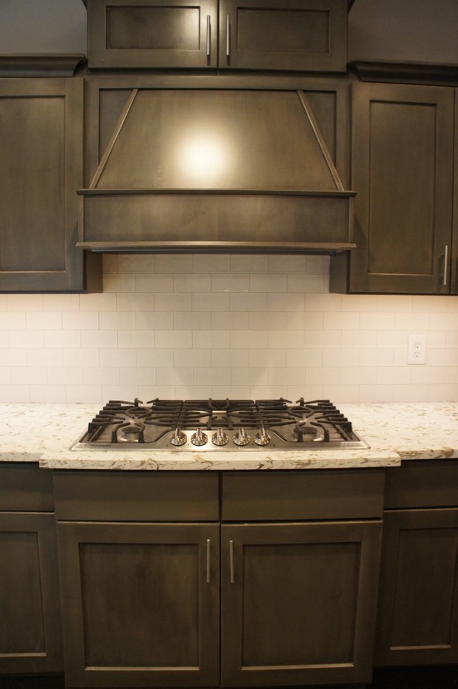 Example of a transitional u-shaped eat-in kitchen design with a farmhouse sink, flat-panel cabinets, white backsplash, ceramic backsplash, stainless steel appliances and an island