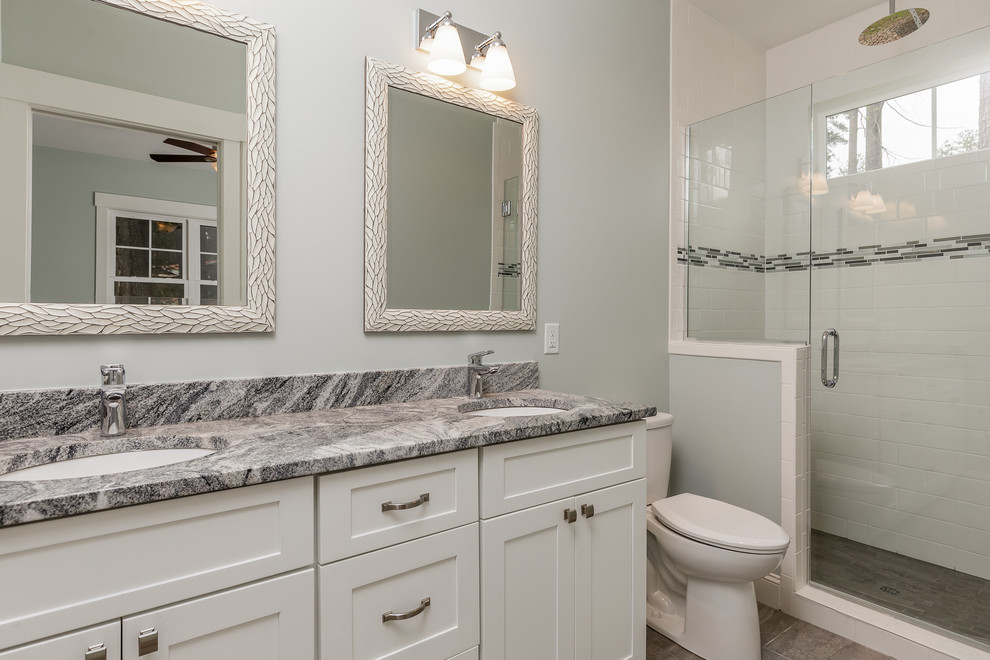 This is an example of a mid-sized arts and crafts 3/4 bathroom in Raleigh with white cabinets, a corner tub, an open shower, a one-piece toilet, black tile, gray tile, white tile, marble, blue walls, ceramic floors, a drop-in sink, marble benchtops, beige floor and an open shower.