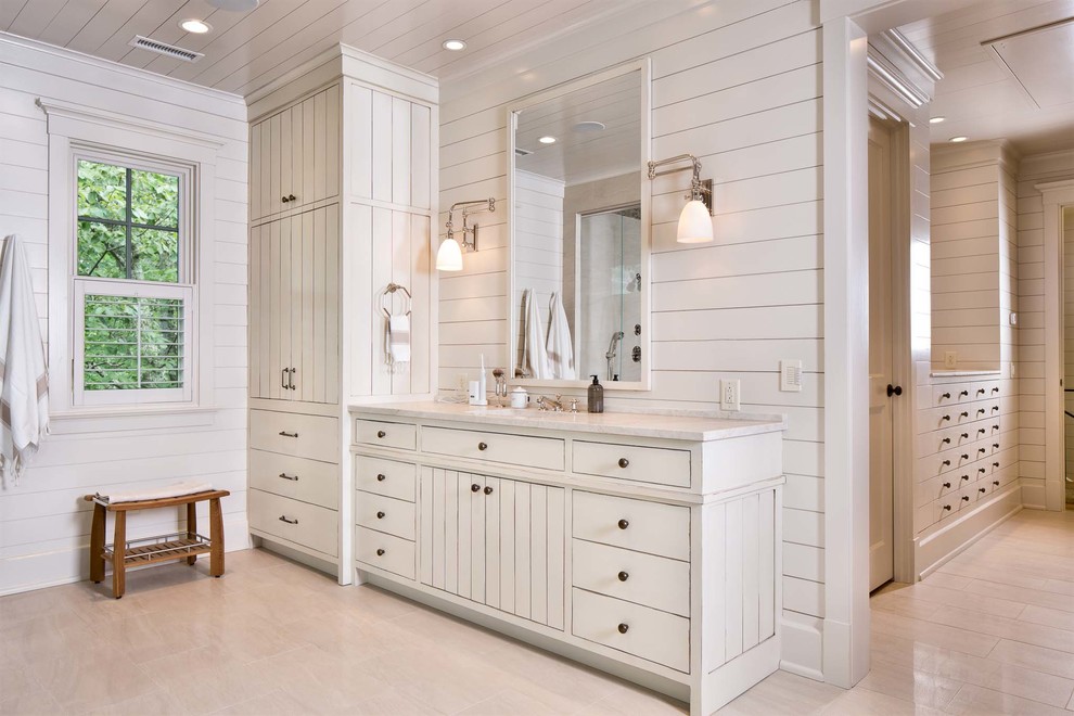 This is an example of an expansive traditional master bathroom in Nashville with an undermount sink, furniture-like cabinets, white cabinets, marble benchtops, a freestanding tub, a corner shower, a two-piece toilet, white walls and light hardwood floors.