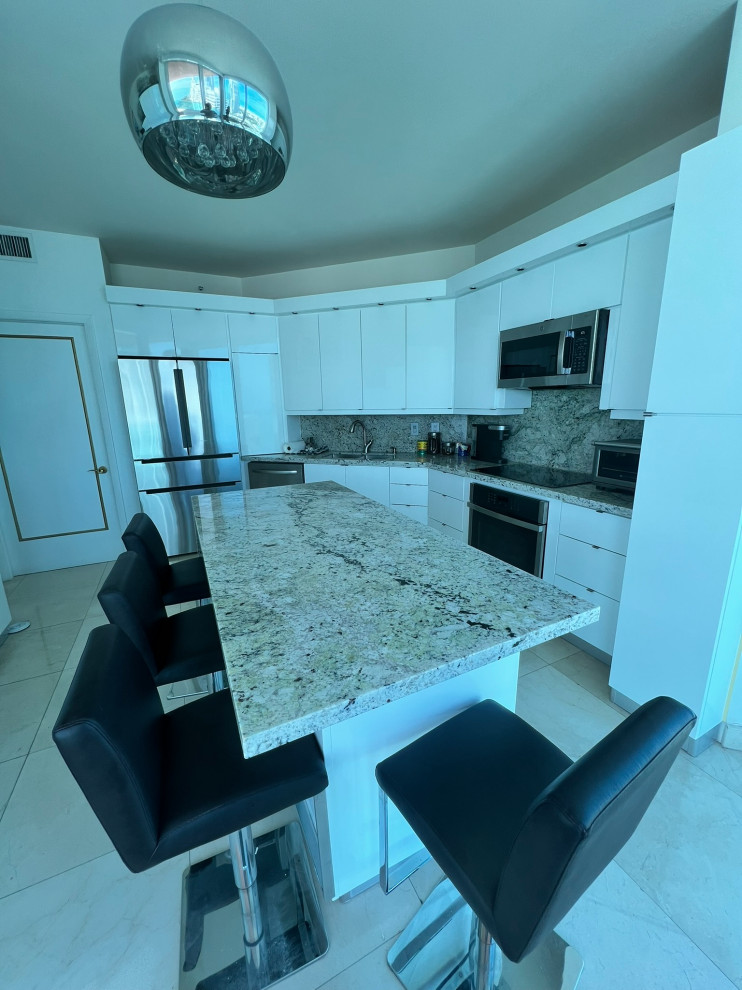 Example of a mid-sized minimalist galley eat-in kitchen design in Miami with white cabinets, granite countertops, granite backsplash and an island