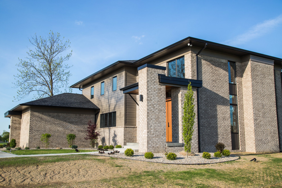 Großes, Zweistöckiges Modernes Einfamilienhaus mit unterschiedlichen Fassadenmaterialien, brauner Fassadenfarbe, Flachdach, Schindeldach, schwarzem Dach und Verschalung in Indianapolis