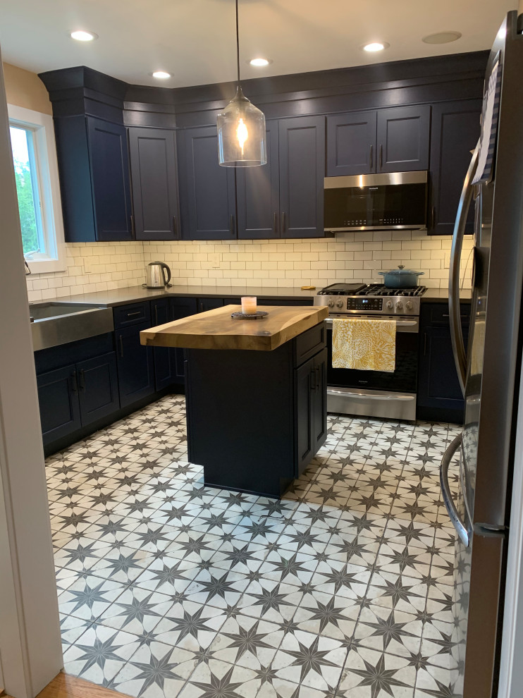 This is an example of a small contemporary u-shaped eat-in kitchen in Philadelphia with a farmhouse sink, shaker cabinets, blue cabinets, quartz benchtops, white splashback, subway tile splashback, stainless steel appliances, linoleum floors, with island, white floor and grey benchtop.