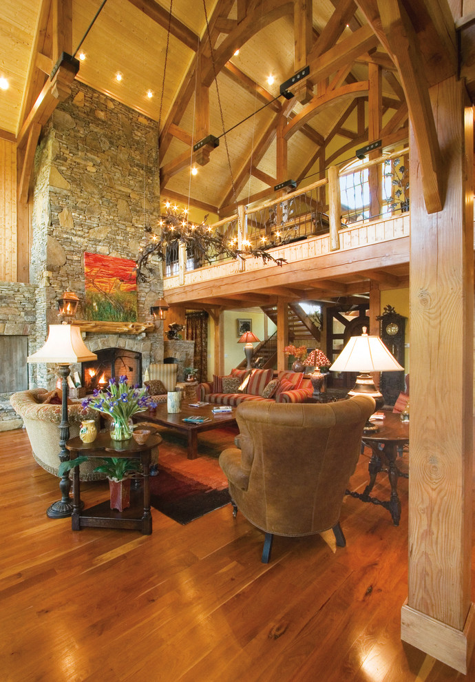Photo of a large arts and crafts loft-style living room in Other with brown walls, medium hardwood floors, a standard fireplace, a stone fireplace surround and a concealed tv.
