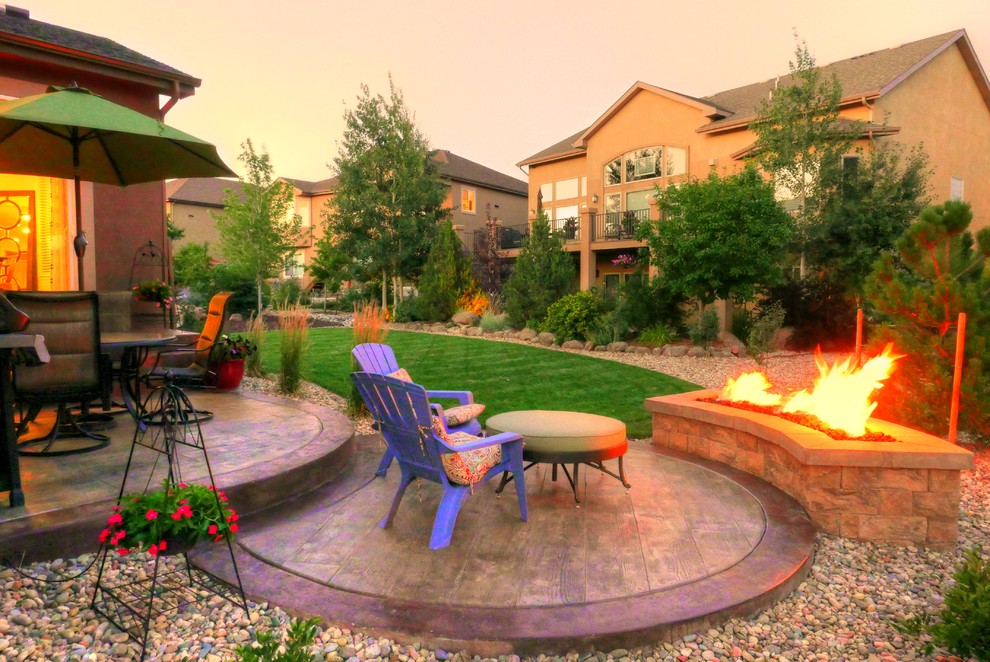 Small eclectic backyard patio in Denver with a fire feature, stamped concrete and no cover.