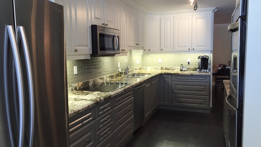 This is an example of a mid-sized transitional galley eat-in kitchen in Toronto with an undermount sink, raised-panel cabinets, white cabinets, granite benchtops, green splashback, glass tile splashback, stainless steel appliances, dark hardwood floors and a peninsula.