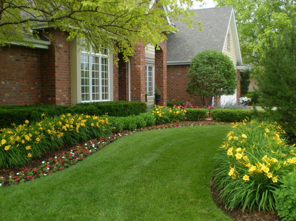 Photo of a mid-sized traditional front yard full sun driveway for summer in Chicago with with flowerbed and brick pavers.