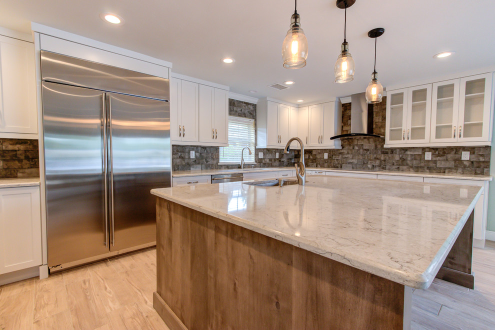 Large transitional u-shaped porcelain tile and brown floor enclosed kitchen photo with an undermount sink, shaker cabinets, white cabinets, quartz countertops, brown backsplash, stainless steel appliances, an island and beige countertops