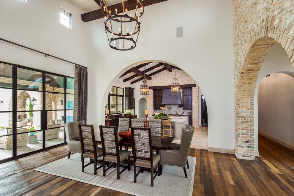 This is an example of a mediterranean dining room in Austin with white walls, medium hardwood floors and no fireplace.