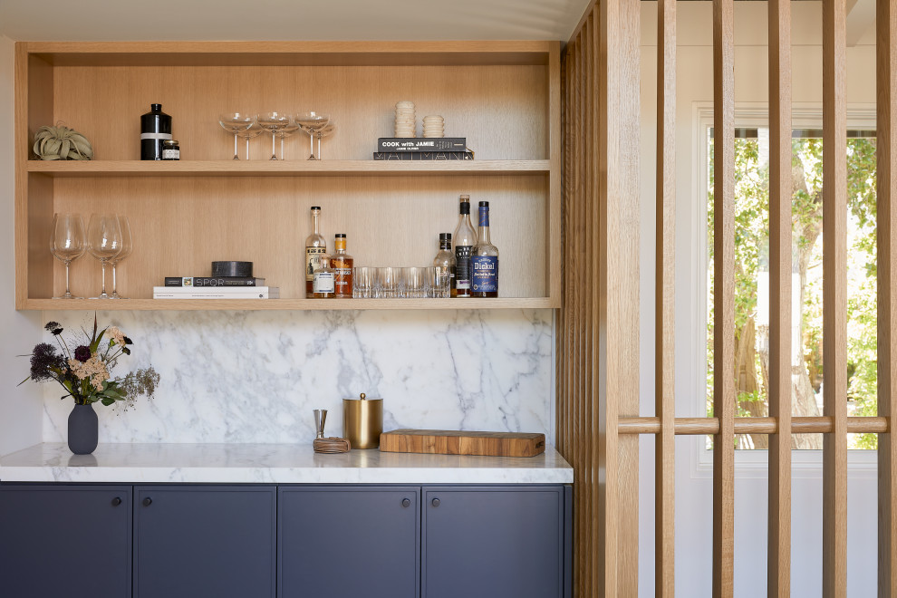 Inspiration for a small midcentury single-wall home bar in San Francisco with no sink, shaker cabinets, blue cabinets, marble benchtops, white splashback, marble splashback, light hardwood floors, brown floor and white benchtop.