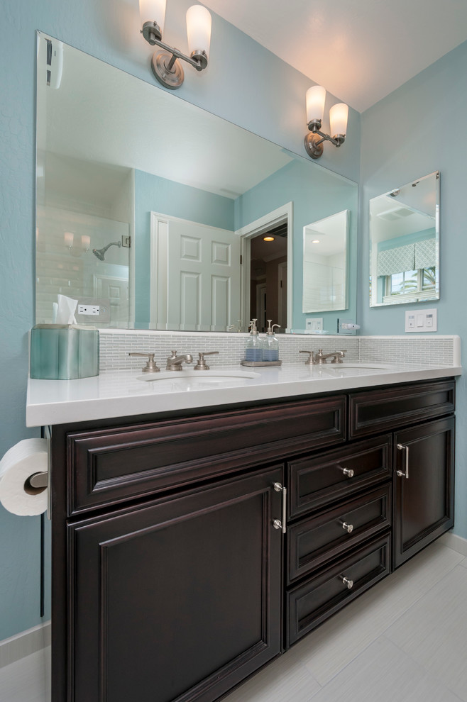 Photo of a mid-sized traditional kids bathroom in San Francisco with an undermount sink, recessed-panel cabinets, dark wood cabinets, engineered quartz benchtops, an alcove shower, a one-piece toilet, white tile, ceramic tile, blue walls and porcelain floors.