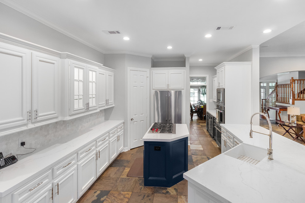 Mid-sized transitional u-shaped eat-in kitchen in Houston with a farmhouse sink, recessed-panel cabinets, white cabinets, quartz benchtops, white splashback, limestone splashback, stainless steel appliances, slate floors, with island, brown floor and white benchtop.