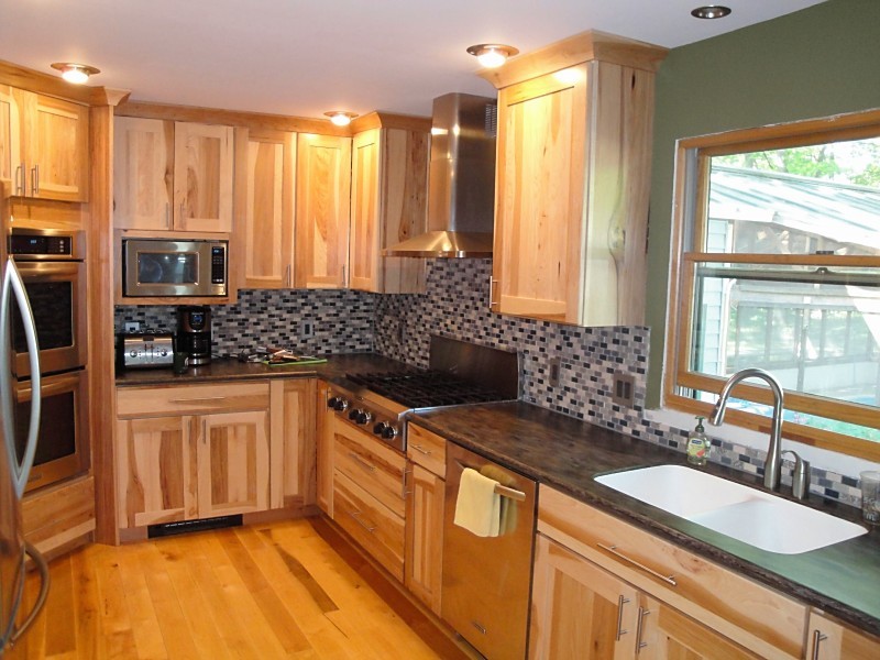 Inspiration for a mid-sized rustic u-shaped light wood floor eat-in kitchen remodel with an undermount sink, flat-panel cabinets, light wood cabinets, solid surface countertops, stainless steel appliances, a peninsula and brown countertops